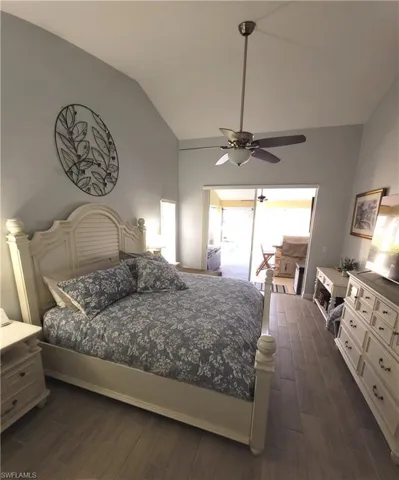 Bedroom featuring ceiling fan, light wood-style tile flooring, and vaulted ceiling and access to lanai