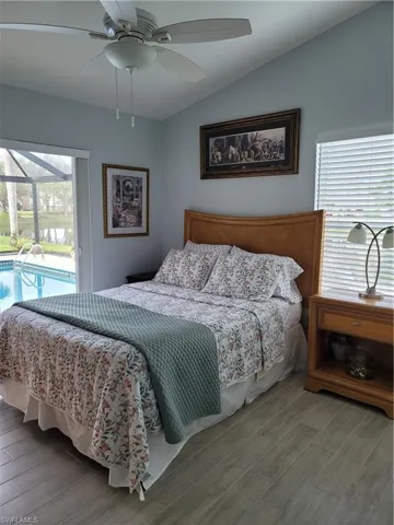 Bedroom featuring hardwood / wood-style floors, ceiling fan, access to outside, and vaulted ceiling