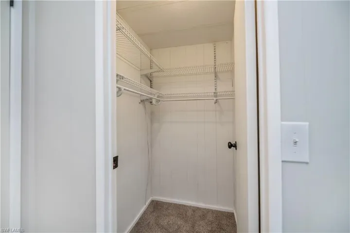 Spacious closet featuring dark colored carpet