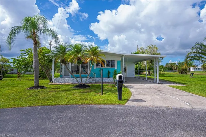 Manufactured / mobile home with a front yard, driveway, and a carport