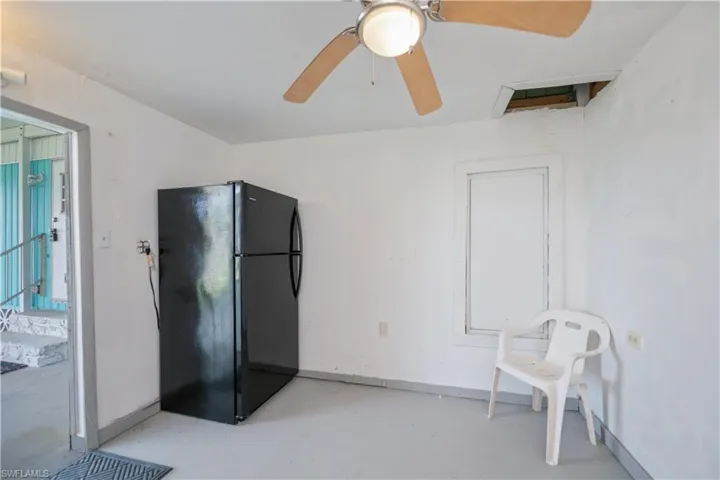 Kitchen with freestanding refrigerator, finished concrete floors, and a ceiling fan