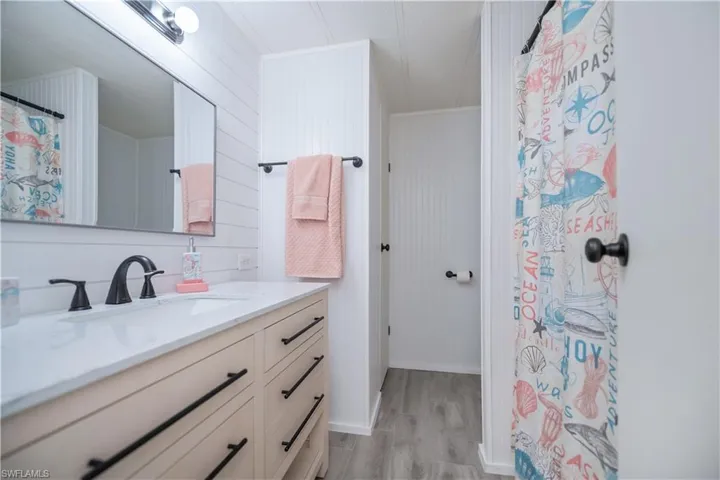 Bathroom featuring vanity, wooden walls, light wood-style flooring, and curtained shower