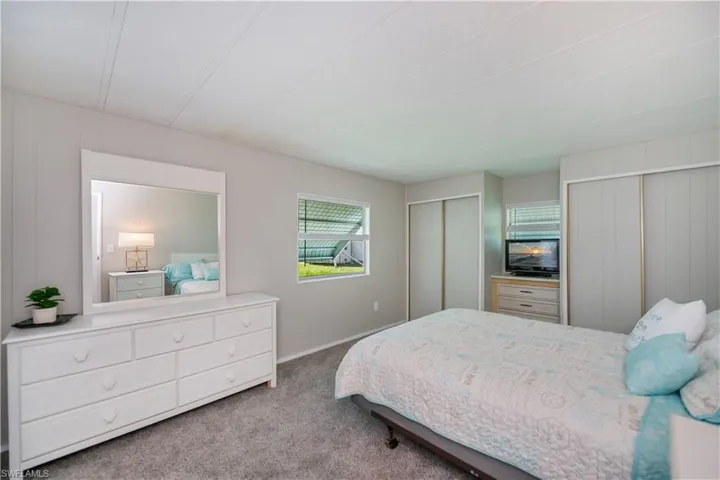 Bedroom with multiple closets, carpet floors, and wooden walls