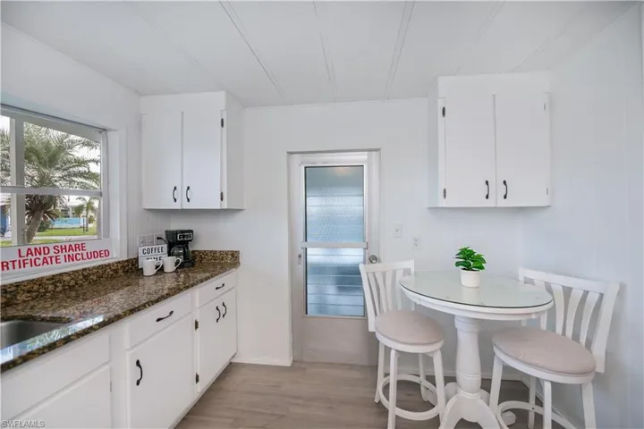 Kitchen featuring plenty of natural light, light wood-type flooring, white cabinets, and dark stone countertops
