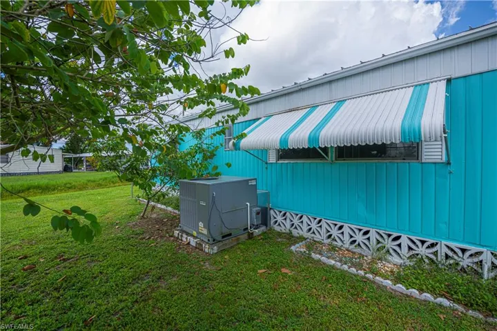 View of side of property featuring a lawn and a cooling unit