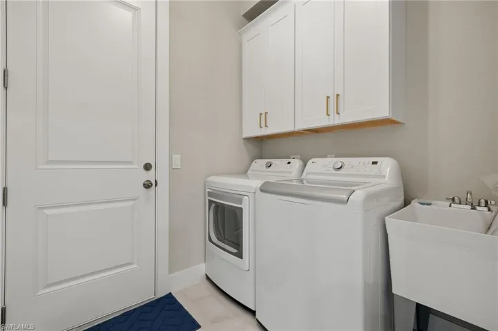 Washroom featuring light tile patterned floors, separate washer and dryer, cabinets, and sink