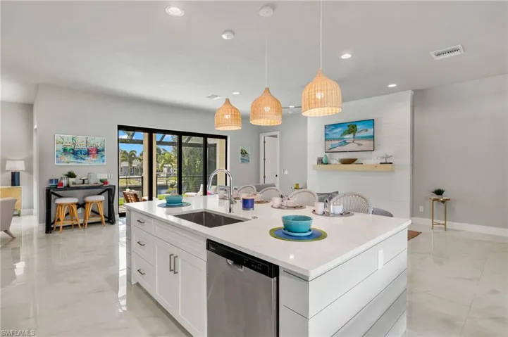 Kitchen with pendant lighting, a center island with sink, sink, stainless steel dishwasher, and white cabinets