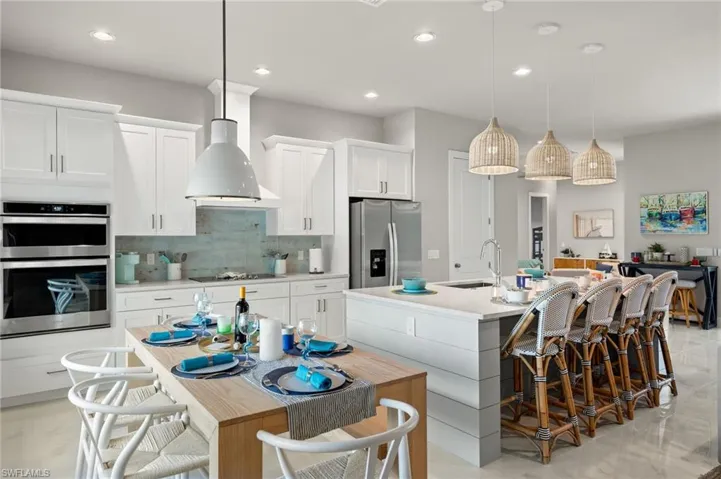 Kitchen with appliances with stainless steel finishes, an island with sink, white cabinetry, and sink