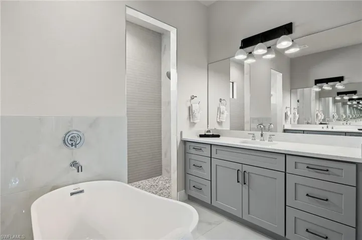 Bathroom with tile walls, separate shower and tub, and vanity