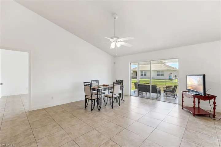 Dining room featuring light tile patterned flooring, high vaulted ceiling, a ceiling fan, and baseboards