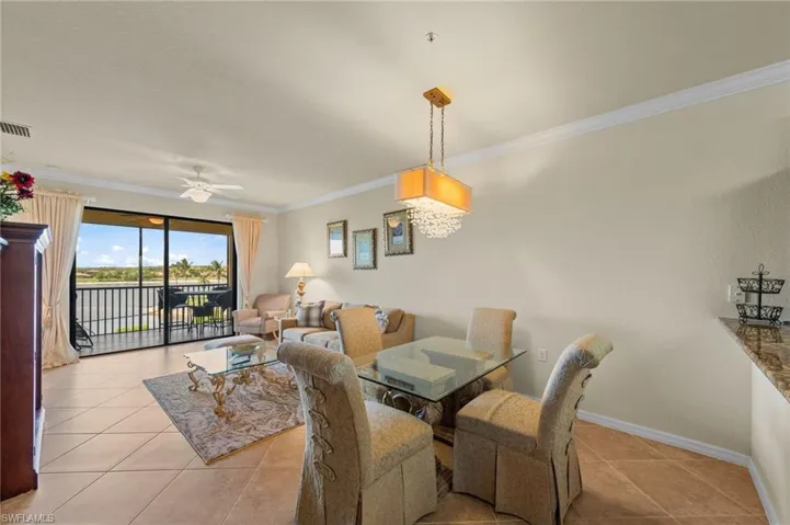 Open-concept living and dining area featuring tile flooring, crown molding, and a chandelier with crystal accents