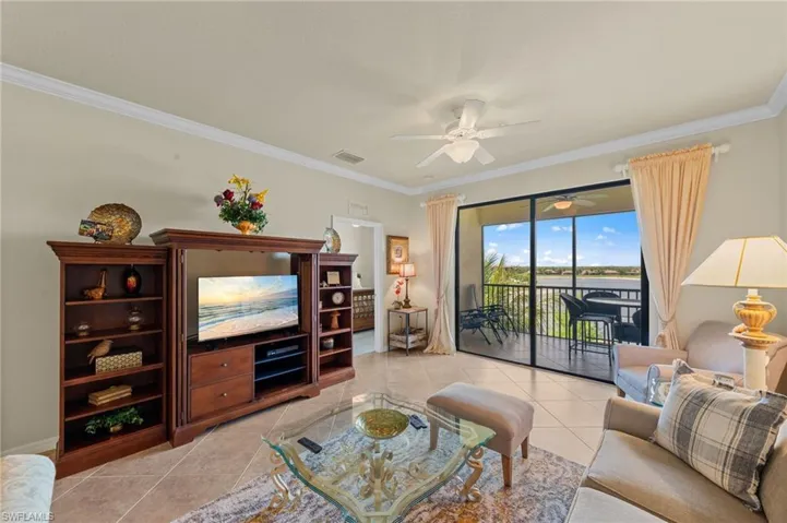 Expansive living area featuring large format tile flooring, crown molding, and a ceiling fan