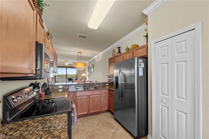 Kitchen featuring wood cabinetry, stainless steel appliances, granite countertops, and tile flooring