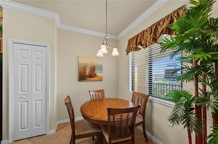Dining area featuring crown molding, a window with horizontal blinds, and a multi-light pendant fixture