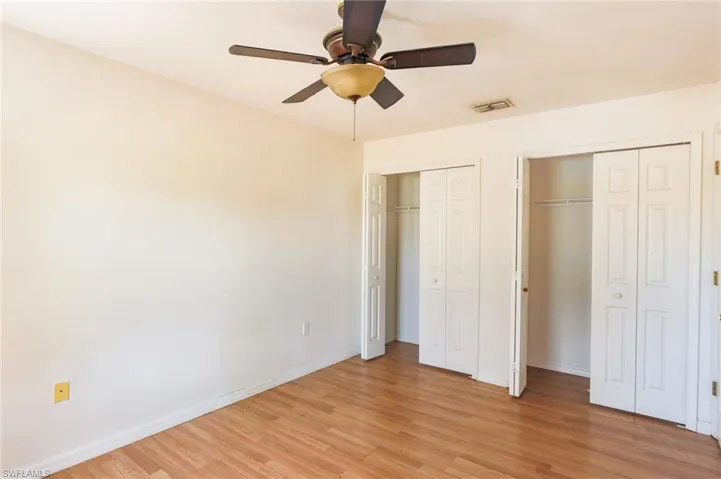 Unfurnished bedroom with two closets, light wood finished floors, and a ceiling fan