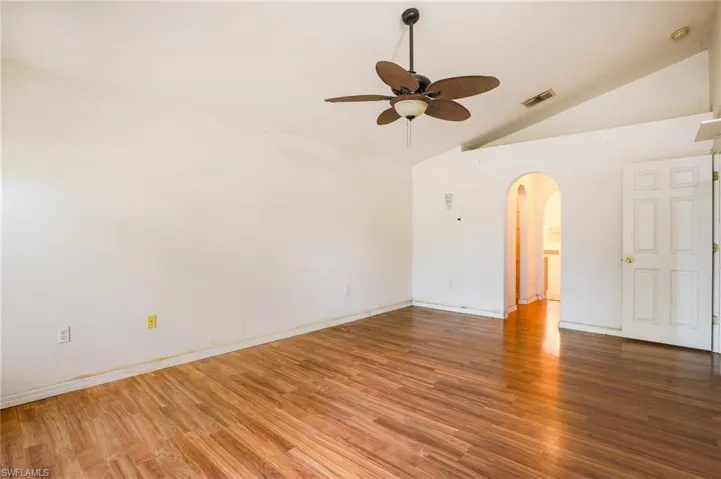 Spare room with arched walkways, lofted ceiling, a ceiling fan, and wood finished floors
