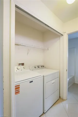 Laundry area with light tile patterned floors and separate washer and dryer