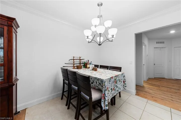 Dining space featuring a chandelier, ornamental molding, light tile patterned floors, and baseboards