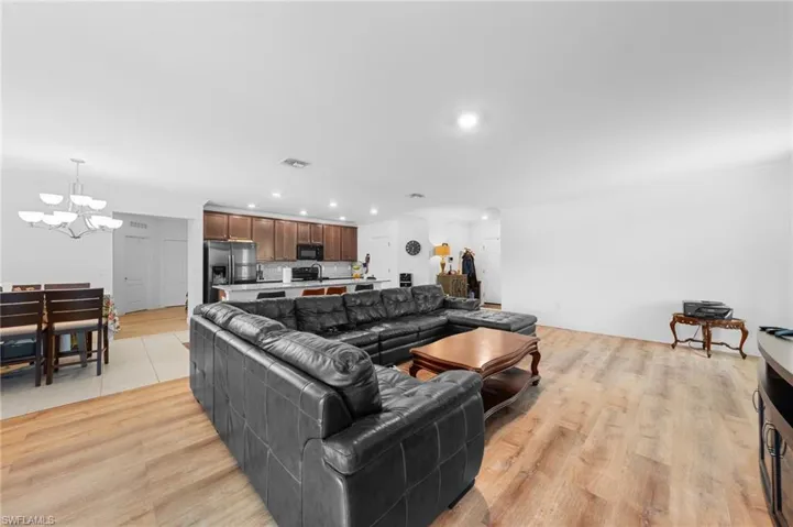 Living room with a chandelier, recessed lighting, ornamental molding, and light wood-style flooring
