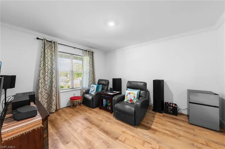 Sitting room with crown molding, light wood-style flooring, and an office area