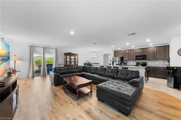 Living room with a chandelier, recessed lighting, light wood-style flooring, and crown molding