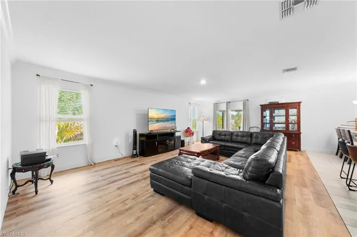 Living area with light wood finished floors, ornamental molding, and baseboards