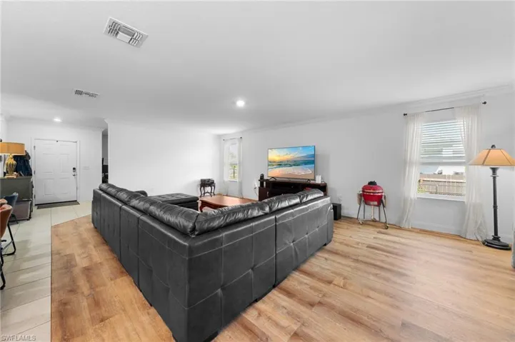 Living area with light wood-type flooring, recessed lighting, and ornamental molding
