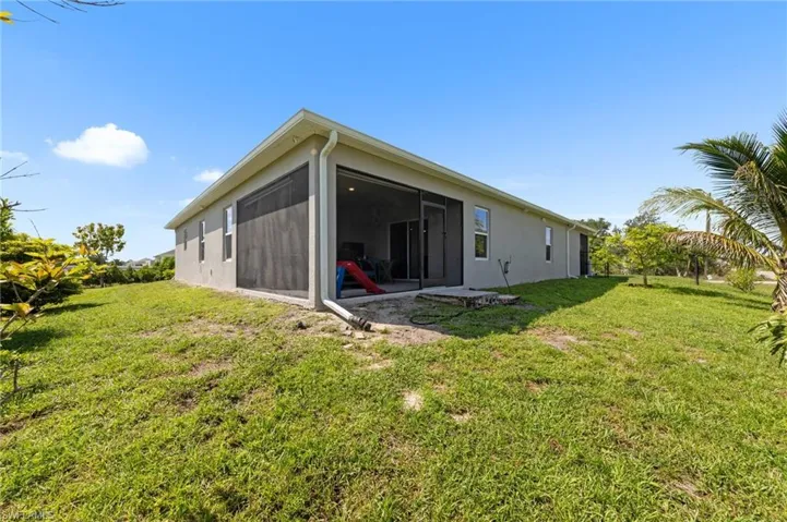 Back of house with a sunroom, a yard, and stucco siding