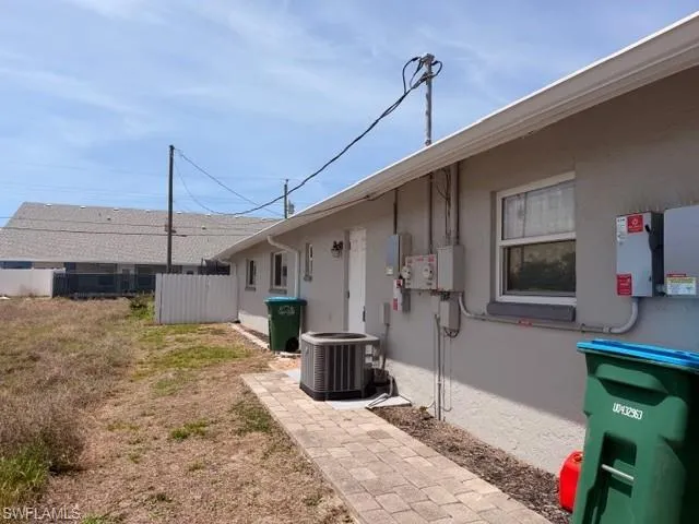 Side view of the duplex showing clean light gray stucco with white trim — well-maintained throughout