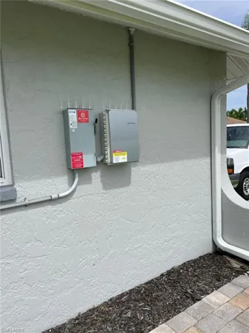 Exterior utility wall with electrical boxes and bird deterrent spikes — practical details showing a well-managed property