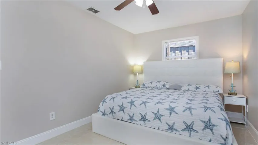 Tiled bedroom with baseboards, visible vents, and a ceiling fan