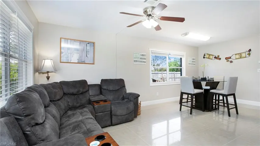 Living room with light tile patterned flooring, baseboards, and ceiling fan