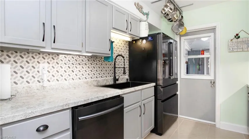 Kitchen with tasteful backsplash, baseboards, a sink, dishwashing machine, and fridge with ice dispenser