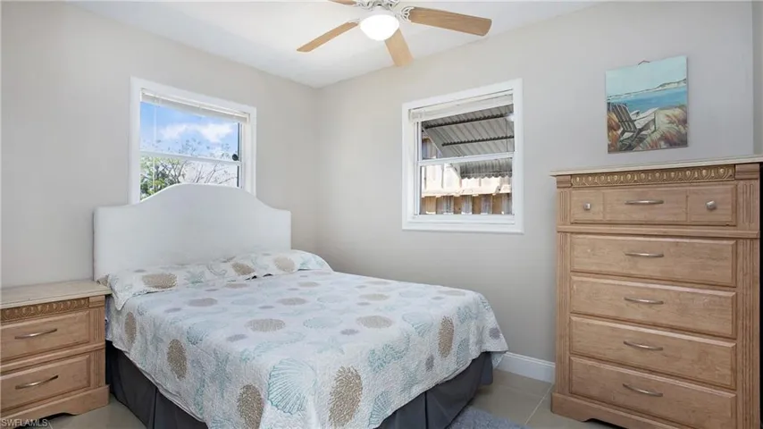 Bedroom featuring light tile patterned floors, baseboards, and ceiling fan