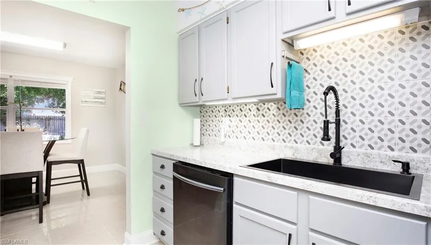 Kitchen with tasteful backsplash, light tile patterned floors, a sink, dishwasher, and light stone countertops