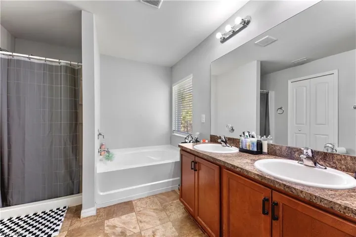 Bathroom with tile patterned floors, double vanity, and a bath