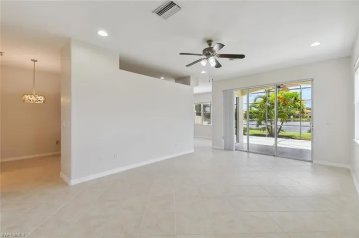 Unfurnished room with ceiling fan with notable chandelier and light tile patterned floors