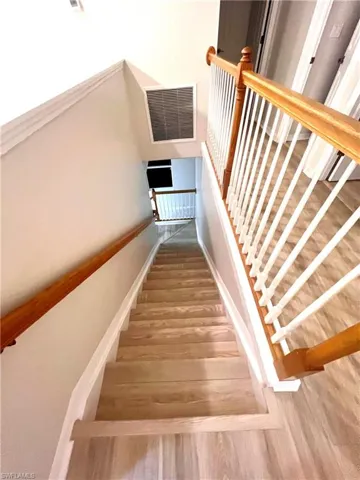 Stairway with a high ceiling and hardwood / wood-style flooring