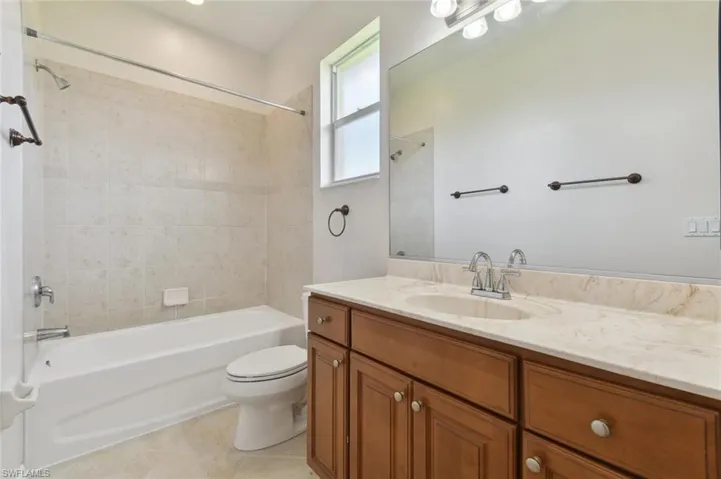 Full bathroom with tile patterned flooring, toilet, vanity, and tiled shower / bath