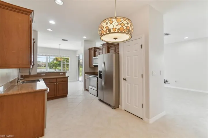 Kitchen featuring light tile patterned flooring, stainless steel appliances, hanging light fixtures, and sink