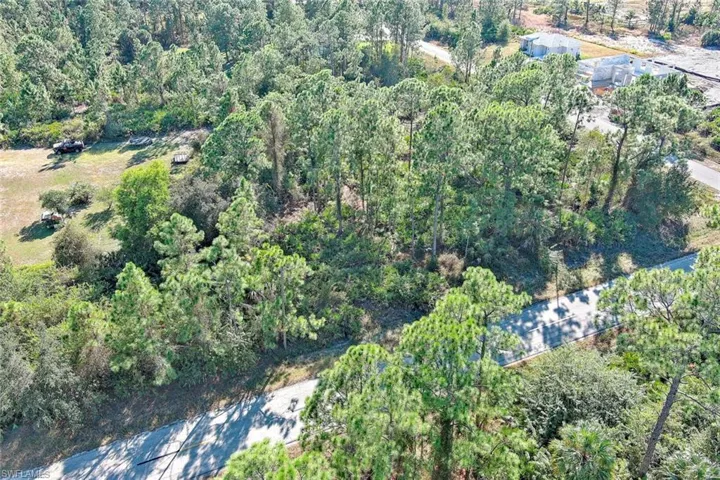 Aerial view of property and surrounding area with a forest