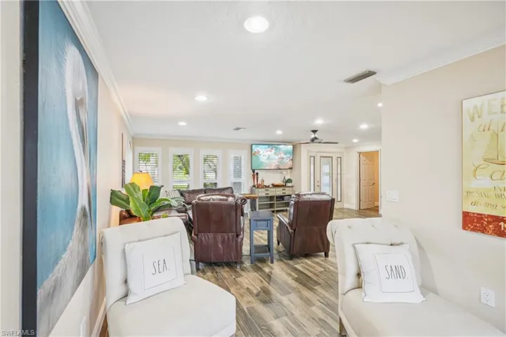 Living area featuring ornamental molding, wood finished floors, recessed lighting, and a ceiling fan