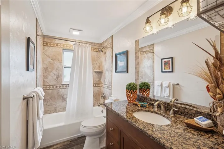 Bathroom featuring ornamental molding, vanity, shower / bath combo with shower curtain, and wood finished floors