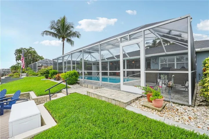 Back of house with a patio, a lawn, an outdoor pool, and glass enclosure