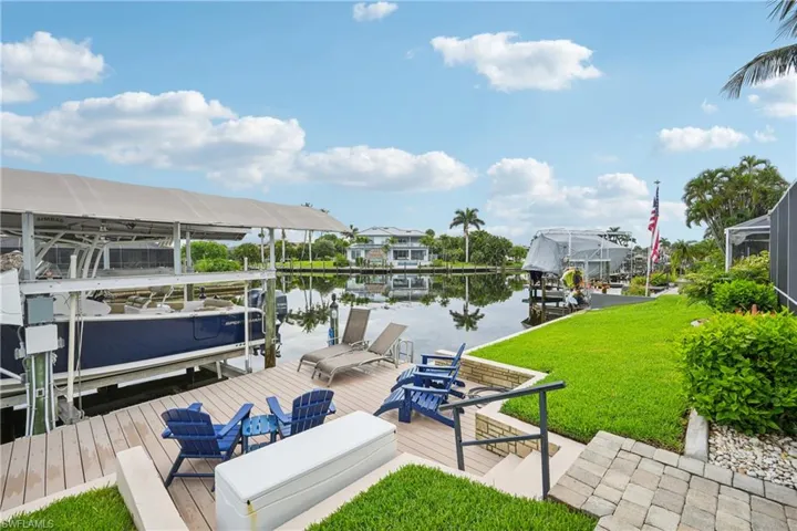 Dock area with boat lift, a water view, and a yard