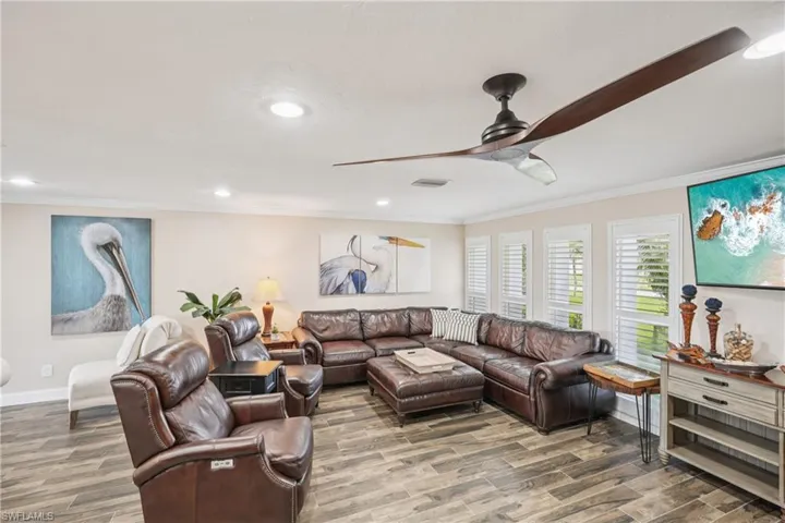 Living room with crown molding, a ceiling fan, wood finished floors, and recessed lighting