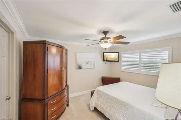 Bedroom featuring light carpet, a ceiling fan, and crown molding