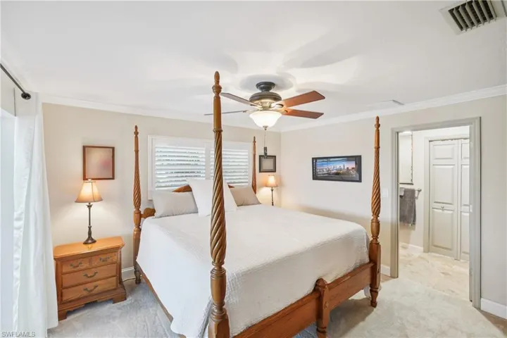 Bedroom with ornamental molding, light carpet, and a ceiling fan