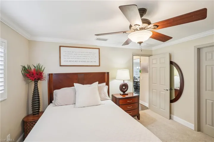 Bedroom with crown molding, light colored carpet, and ceiling fan