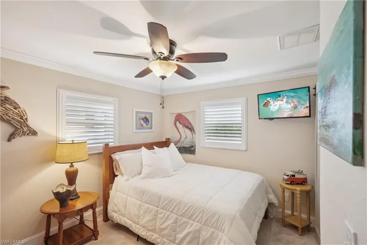 Carpeted bedroom with crown molding, multiple windows, and ceiling fan